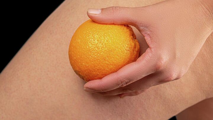 Женщина с апельсином на фоне бедра