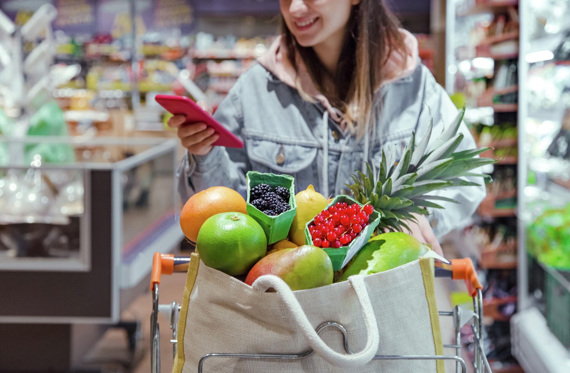 Девушка покупает продукты в супермаркете с телефоном в руках - rnews, 1920, 18.10.2022