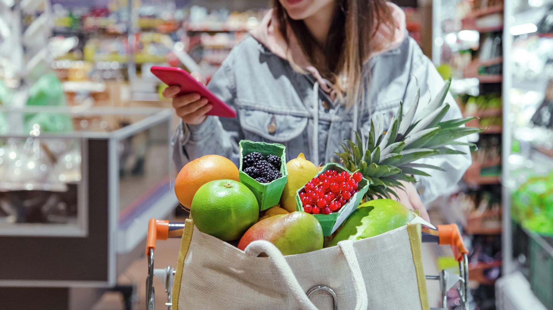 Девушка покупает продукты в супермаркете с телефоном в руках - rnews, 1920, 25.12.2023
