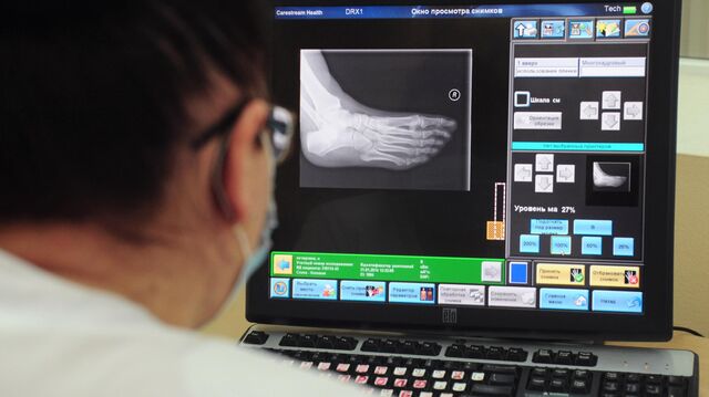 Рентгенолаборант просматривает снимки на экране монитора в отделение неотложной травматологии и ортопедии