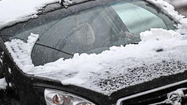 Женщина за рулем автомобиля во время снегопада
