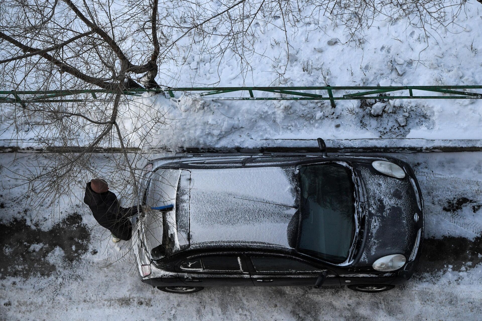 Женщина очищает машину от снега во дворе жилого дома в морозный день - rnews, 1920, 16.12.2022
